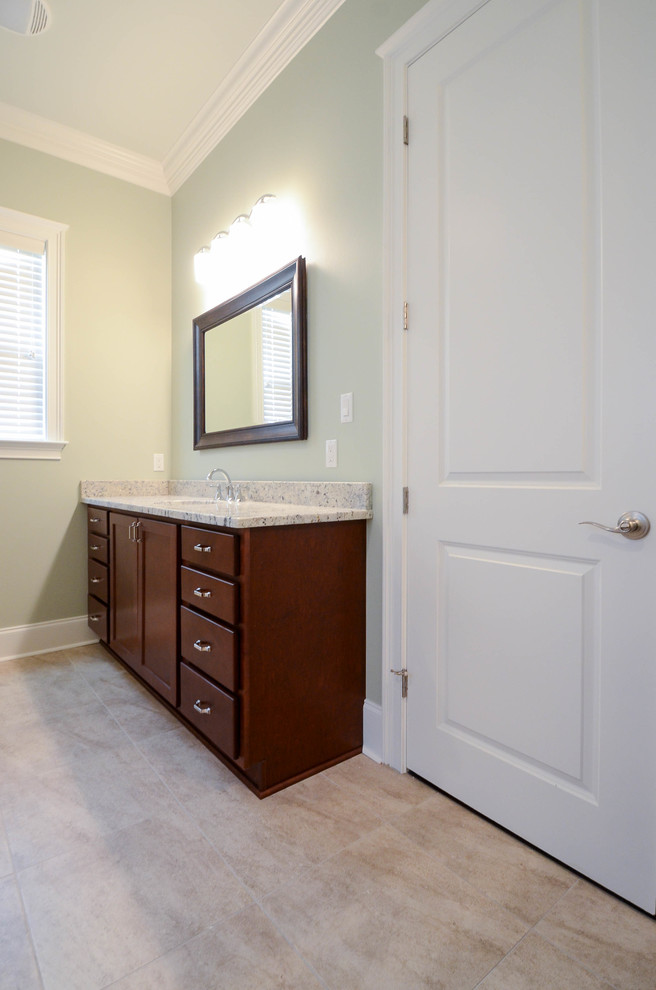 Photo of a medium sized classic ensuite bathroom in New Orleans with a submerged sink, flat-panel cabinets, dark wood cabinets, granite worktops, a two-piece toilet, beige tiles, ceramic tiles, green walls and ceramic flooring.