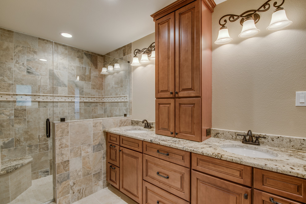 Photo of a medium sized traditional ensuite bathroom in Austin with shaker cabinets, brown cabinets, an alcove shower, a one-piece toilet, beige tiles, porcelain tiles, beige walls, ceramic flooring, a built-in sink, granite worktops, beige floors, a hinged door and beige worktops.