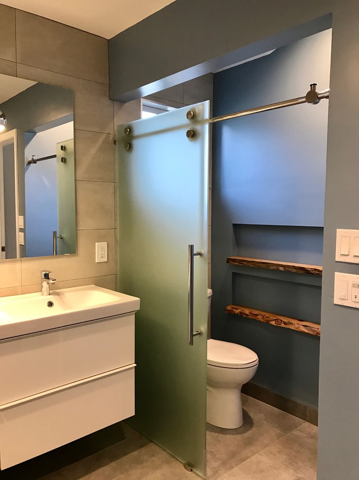 Idée de décoration pour une grande salle de bain principale minimaliste avec un placard à porte plane, des portes de placard blanches, une baignoire indépendante, un espace douche bain, WC à poser, un carrelage gris, des carreaux de porcelaine, un mur bleu, un sol en carrelage de porcelaine, un lavabo intégré, un plan de toilette en surface solide, un sol gris et une cabine de douche à porte battante.