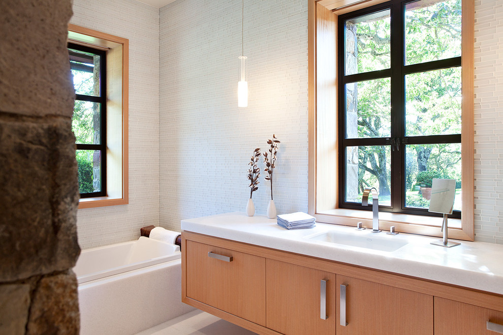 Imagen de cuarto de baño principal contemporáneo grande con armarios con paneles lisos, puertas de armario de madera clara, bañera empotrada, paredes blancas y lavabo bajoencimera
