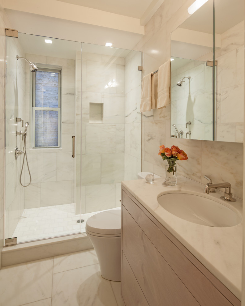 Example of a mid-sized transitional 3/4 white tile and stone tile marble floor alcove shower design in New York with flat-panel cabinets, light wood cabinets, marble countertops, a drop-in sink and white walls