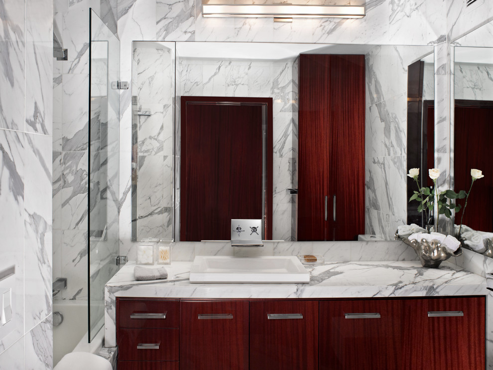 Aménagement d'une salle de bain principale moderne en bois foncé de taille moyenne avec un lavabo posé, un placard à porte plane, un plan de toilette en marbre, une baignoire posée, WC à poser, un carrelage blanc, un carrelage de pierre, un mur blanc et un sol en marbre.