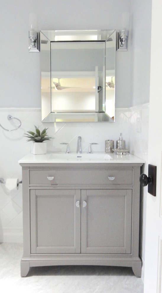 Inredning av ett klassiskt stort en-suite badrum, med ett integrerad handfat, luckor med infälld panel, grå skåp, bänkskiva i akrylsten, ett platsbyggt badkar, en dusch/badkar-kombination, en toalettstol med separat cisternkåpa, vit kakel, keramikplattor, grå väggar och marmorgolv