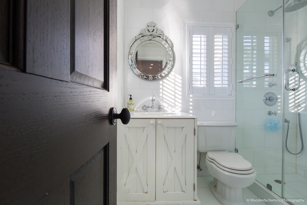 На фото: ванная комната в морском стиле с фасадами с выступающей филенкой, темными деревянными фасадами, душем в нише, белой плиткой, мраморной плиткой, белыми стенами, темным паркетным полом, мраморной столешницей, коричневым полом и душем с распашными дверями