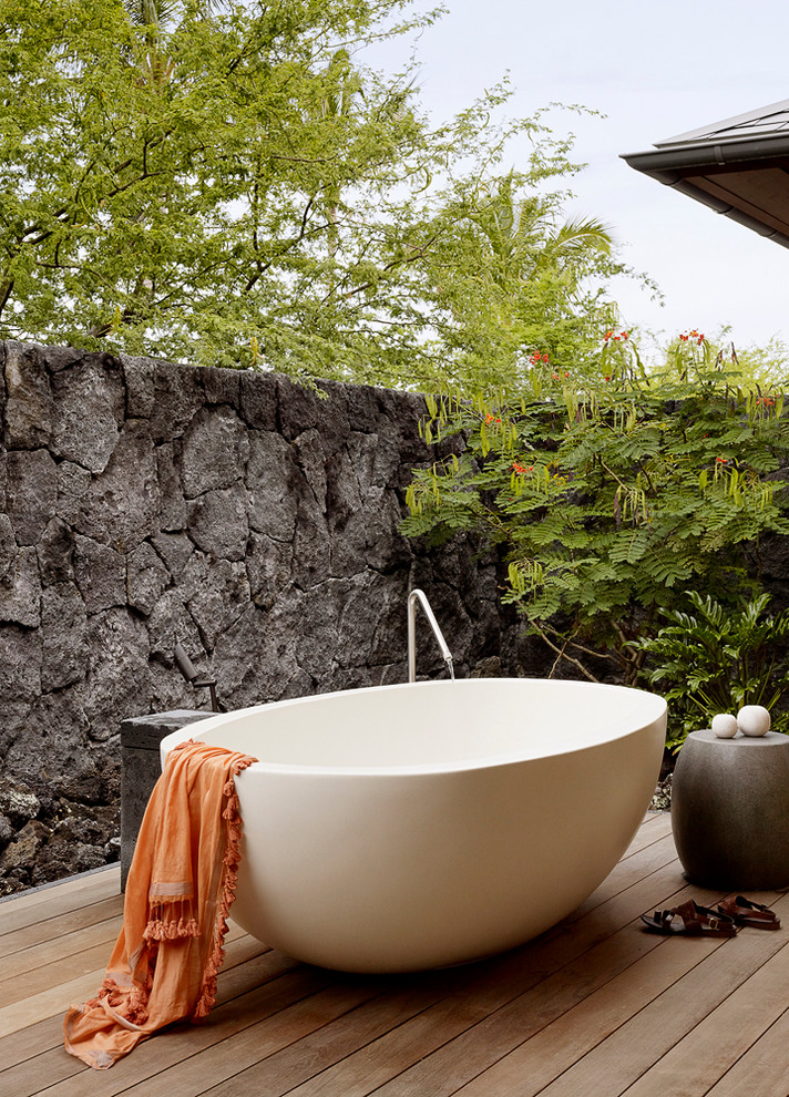 Cette photo montre une salle de bain exotique avec une baignoire indépendante et un mur en pierre.
