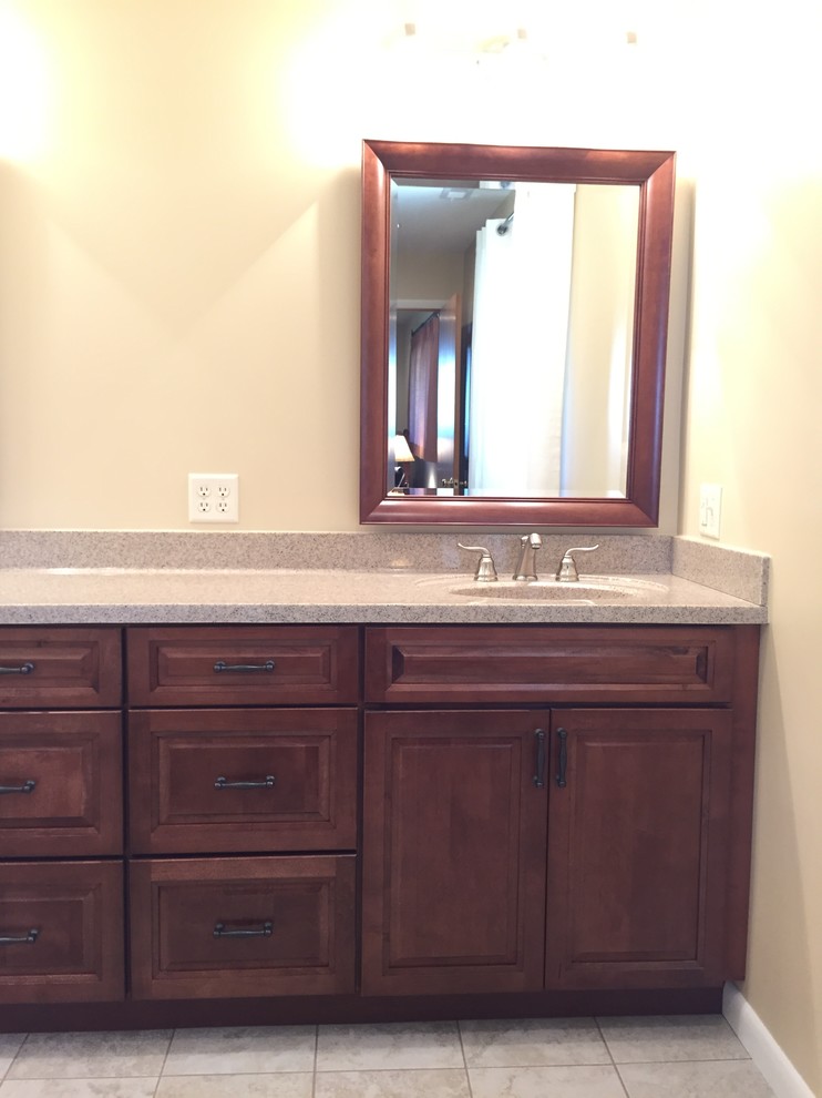 Photo of a traditional ensuite bathroom in Other with an integrated sink, raised-panel cabinets, dark wood cabinets and beige walls.