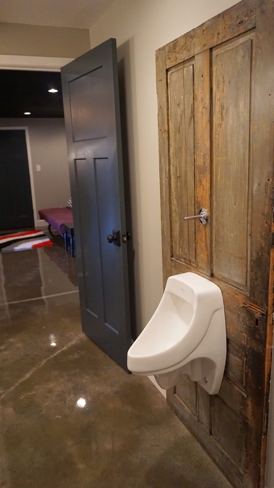 Modelo de cuarto de baño minimalista de tamaño medio con paredes grises, suelo de cemento, lavabo de seno grande, armarios abiertos, puertas de armario negras, encimera de madera, bañera empotrada, combinación de ducha y bañera y urinario
