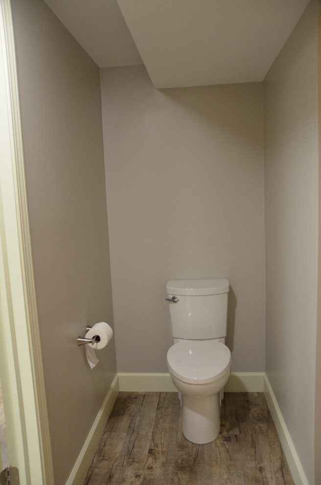 Modelo de aseo contemporáneo de tamaño medio con lavabo encastrado, armarios con paneles con relieve, puertas de armario blancas, encimera de laminado, sanitario de una pieza y paredes grises