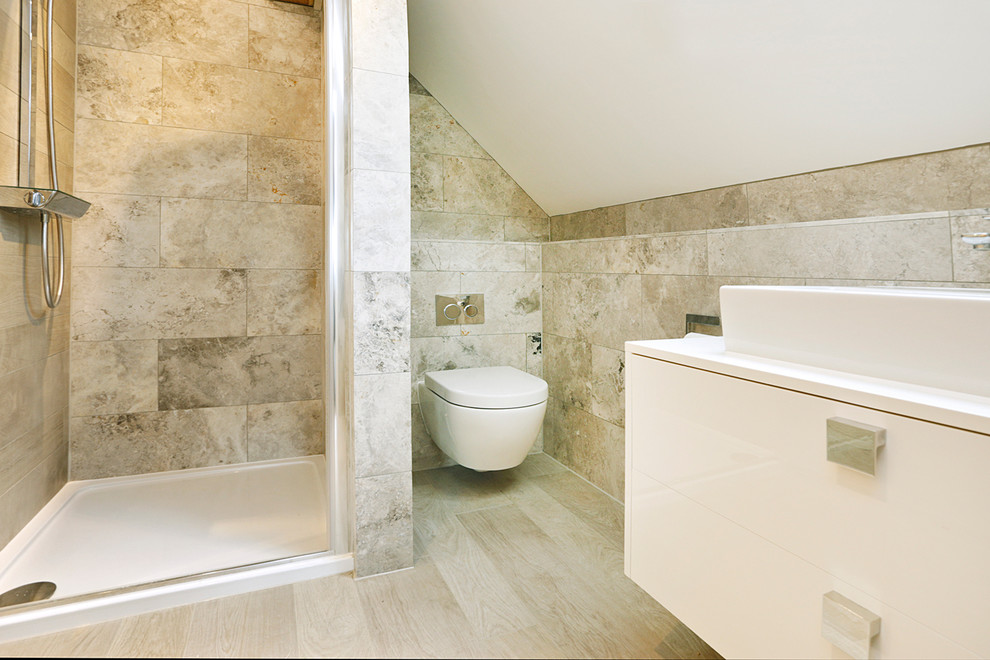 Imagen de cuarto de baño principal contemporáneo pequeño con armarios con paneles lisos, puertas de armario blancas, sanitario de pared, baldosas y/o azulejos grises, baldosas y/o azulejos de piedra y paredes blancas