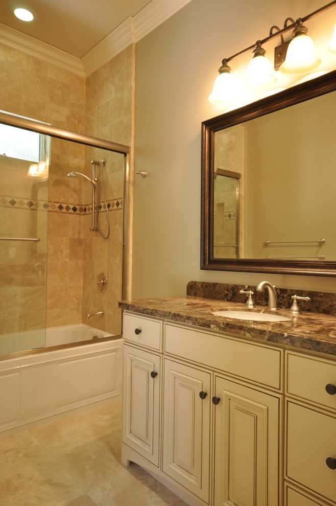 Klassisk inredning av ett badrum, med ett undermonterad handfat, luckor med upphöjd panel, beige skåp, ett badkar i en alkov, en dusch/badkar-kombination och beige kakel