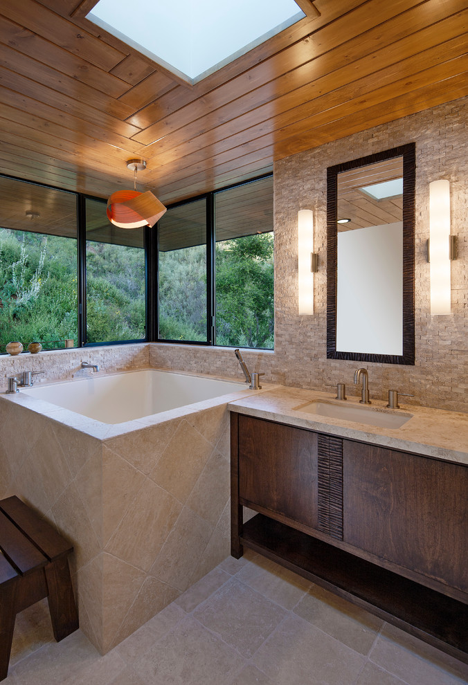 Bild på ett funkis badrum, med skåp i mörkt trä, beige kakel, stenkakel, ett undermonterad handfat, granitbänkskiva, ett japanskt badkar och släta luckor