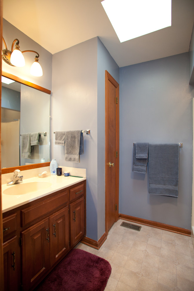 Пример оригинального дизайна: главная ванная комната среднего размера в классическом стиле с монолитной раковиной, фасадами с выступающей филенкой, фасадами цвета дерева среднего тона, угловой ванной, душем над ванной, унитазом-моноблоком, синими стенами и полом из линолеума