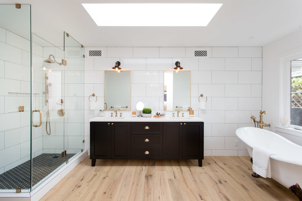 Cette photo montre une salle de bain principale nature en bois foncé avec une baignoire sur pieds, un carrelage blanc, un mur blanc, parquet clair, un lavabo encastré, une cabine de douche à porte battante et un placard à porte shaker.