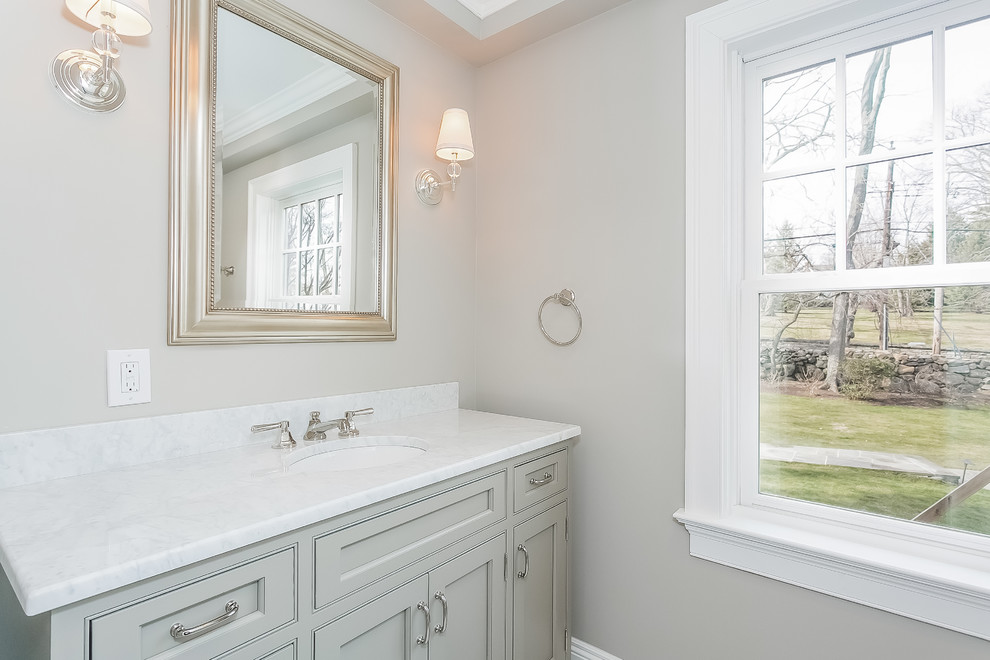 Klassisk inredning av ett litet badrum, med beige skåp, ett undermonterad handfat, marmorbänkskiva, möbel-liknande, ett badkar i en alkov, en dusch/badkar-kombination, vit kakel, tunnelbanekakel, beige väggar och mosaikgolv
