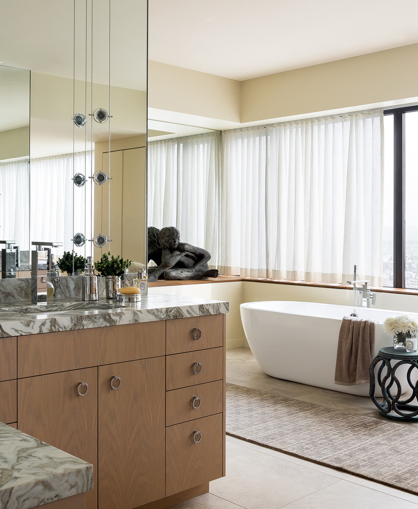 Esempio di una stanza da bagno padronale contemporanea con ante lisce, ante in legno chiaro, vasca freestanding, lavabo sottopiano, top in marmo, top multicolore, pareti beige e pavimento beige