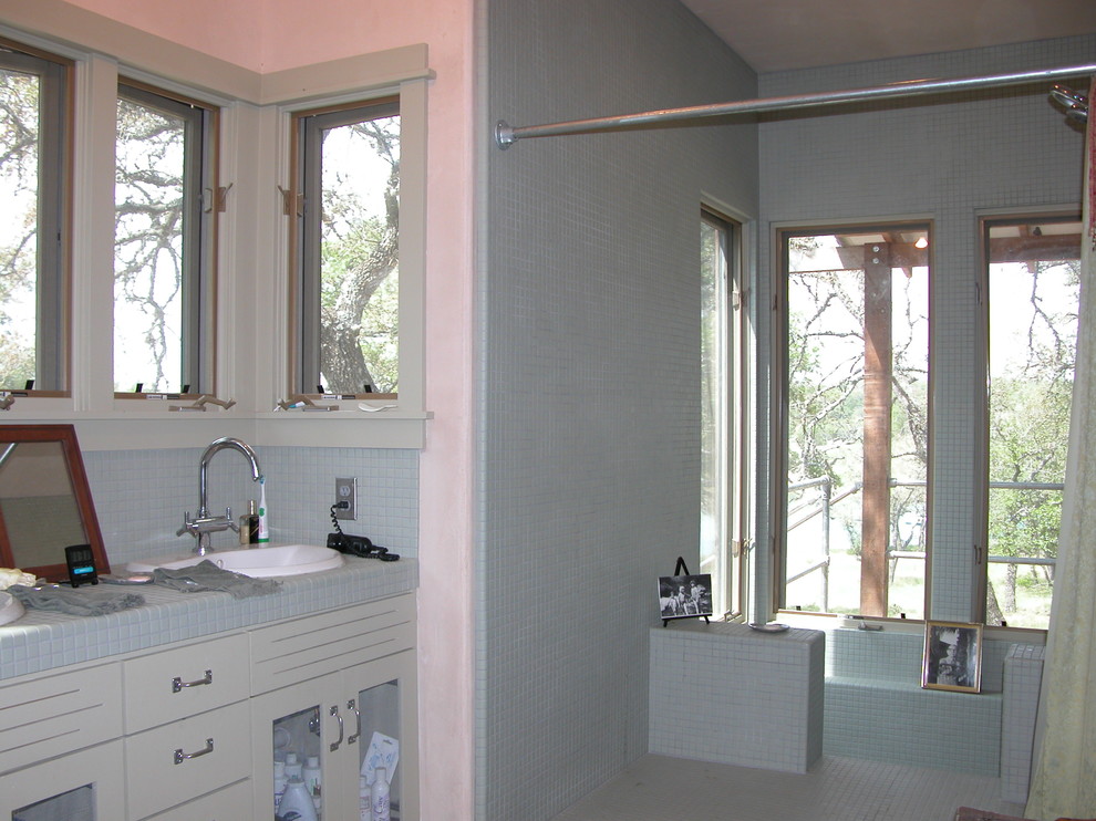 Doorless shower - traditional green tile and mosaic tile doorless shower idea in Austin with a vessel sink, shaker cabinets, tile countertops and a two-piece toilet