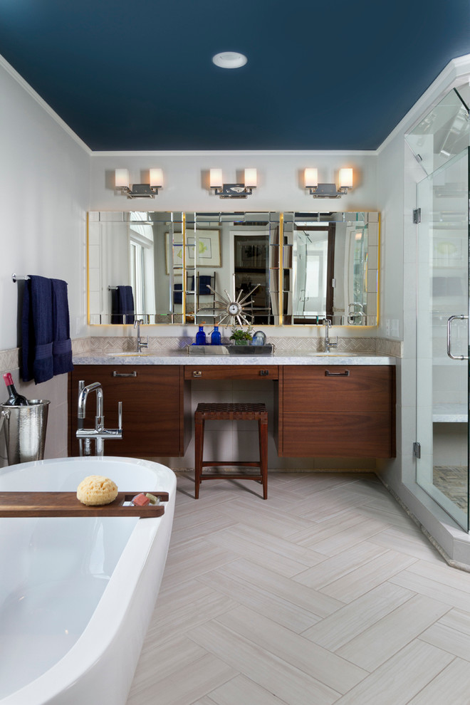 Bild på ett funkis en-suite badrum, med ett undermonterad handfat, släta luckor, skåp i mellenmörkt trä, bänkskiva i onyx, ett fristående badkar, en dubbeldusch, en toalettstol med hel cisternkåpa, grå kakel, porslinskakel, grå väggar och klinkergolv i keramik