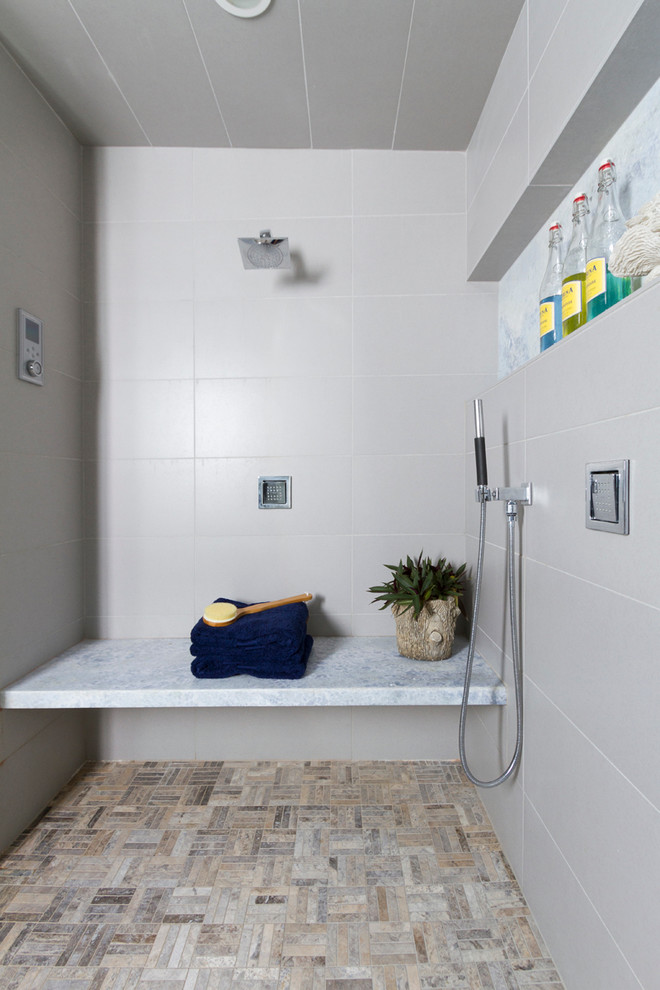 Idéer för att renovera ett funkis en-suite badrum, med ett undermonterad handfat, släta luckor, skåp i mellenmörkt trä, bänkskiva i onyx, ett fristående badkar, en dubbeldusch, en toalettstol med hel cisternkåpa, grå kakel, porslinskakel, grå väggar och klinkergolv i porslin