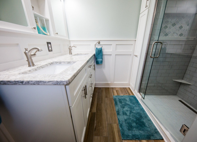 Photo of a medium sized traditional shower room bathroom in Omaha with shaker cabinets, white cabinets, an alcove shower, a two-piece toilet, grey tiles, metro tiles, blue walls, medium hardwood flooring, a submerged sink, granite worktops, brown floors and a hinged door.