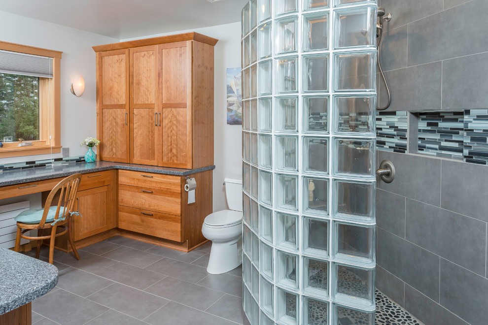 Example of a mid-sized transitional master gray tile and mosaic tile porcelain tile doorless shower design in Other with an undermount sink, recessed-panel cabinets, medium tone wood cabinets, solid surface countertops, a two-piece toilet and gray walls