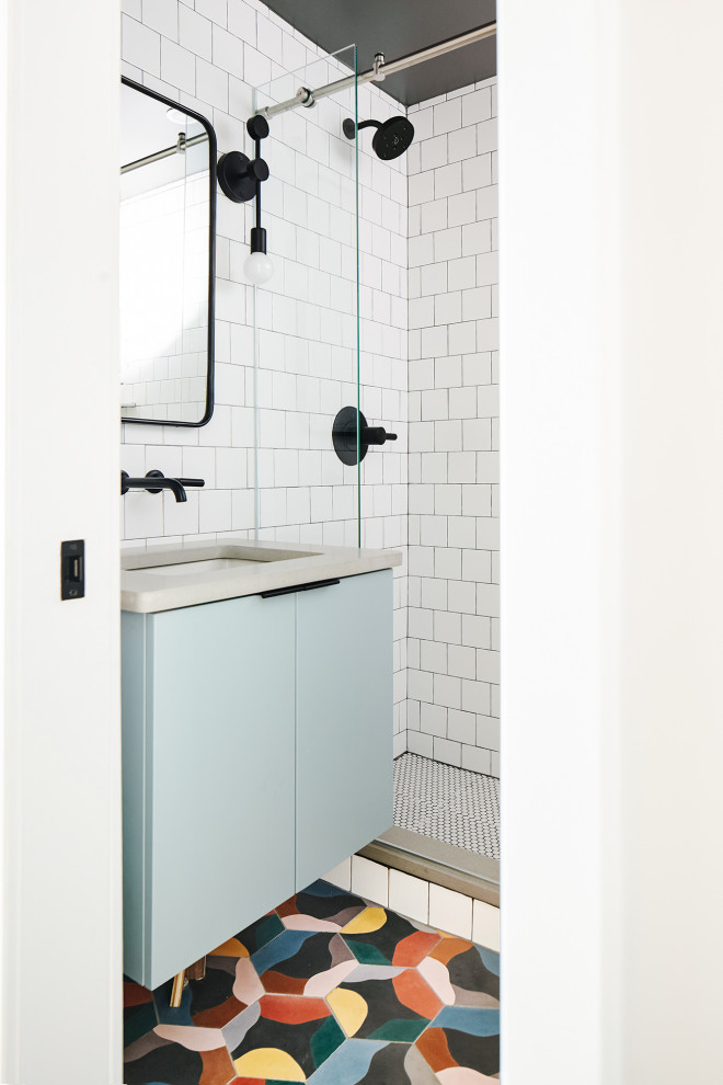 Foto på ett litet funkis grå badrum med dusch, med släta luckor, blå skåp, en dusch i en alkov, en toalettstol med hel cisternkåpa, vit kakel, keramikplattor, vita väggar, cementgolv, ett undermonterad handfat, bänkskiva i betong, flerfärgat golv och dusch med skjutdörr