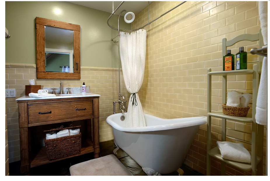 This is an example of a rural bathroom in Sacramento with freestanding cabinets, dark wood cabinets, a freestanding bath, a shower/bath combination, beige tiles, ceramic tiles and green walls.