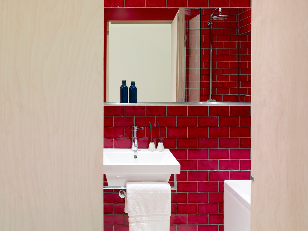 Inspiration för ett funkis badrum för barn, med ett platsbyggt badkar, en hörndusch, en vägghängd toalettstol, röd kakel, keramikplattor, röda väggar, ett väggmonterat handfat, vitt golv och dusch med gångjärnsdörr