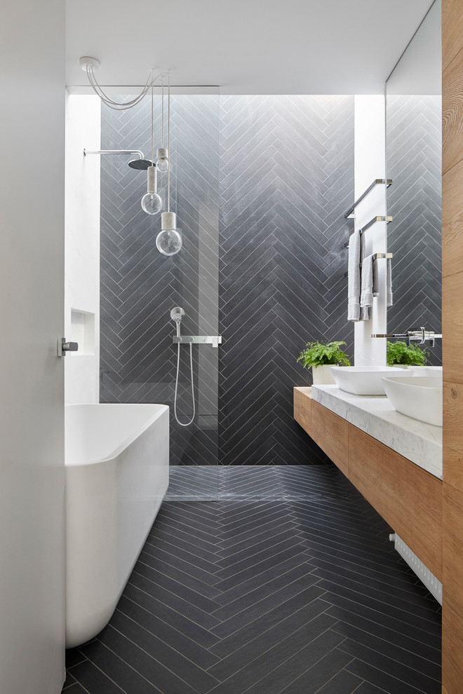 Small contemporary ensuite bathroom in Melbourne with flat-panel cabinets, medium wood cabinets, a freestanding bath, a walk-in shower, a two-piece toilet, black tiles, porcelain tiles, porcelain flooring, a vessel sink, marble worktops, black floors, an open shower and black walls.