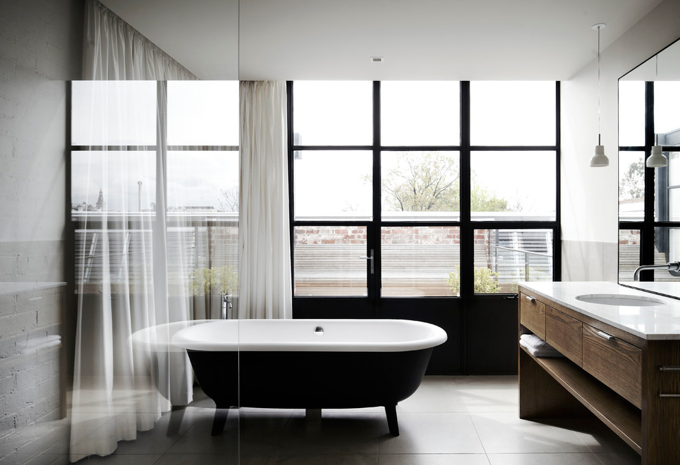 На фото: ванная комната среднего размера в современном стиле с плоскими фасадами, темными деревянными фасадами, отдельно стоящей ванной и врезной раковиной с
