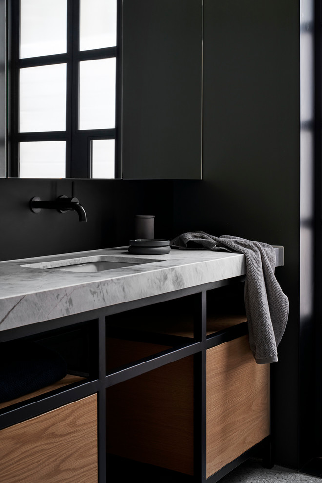 Bild på ett mellanstort funkis grå grått en-suite badrum, med öppna hyllor, skåp i mellenmörkt trä, svart kakel, kakel i metall, svarta väggar, cementgolv, ett undermonterad handfat, marmorbänkskiva och grått golv