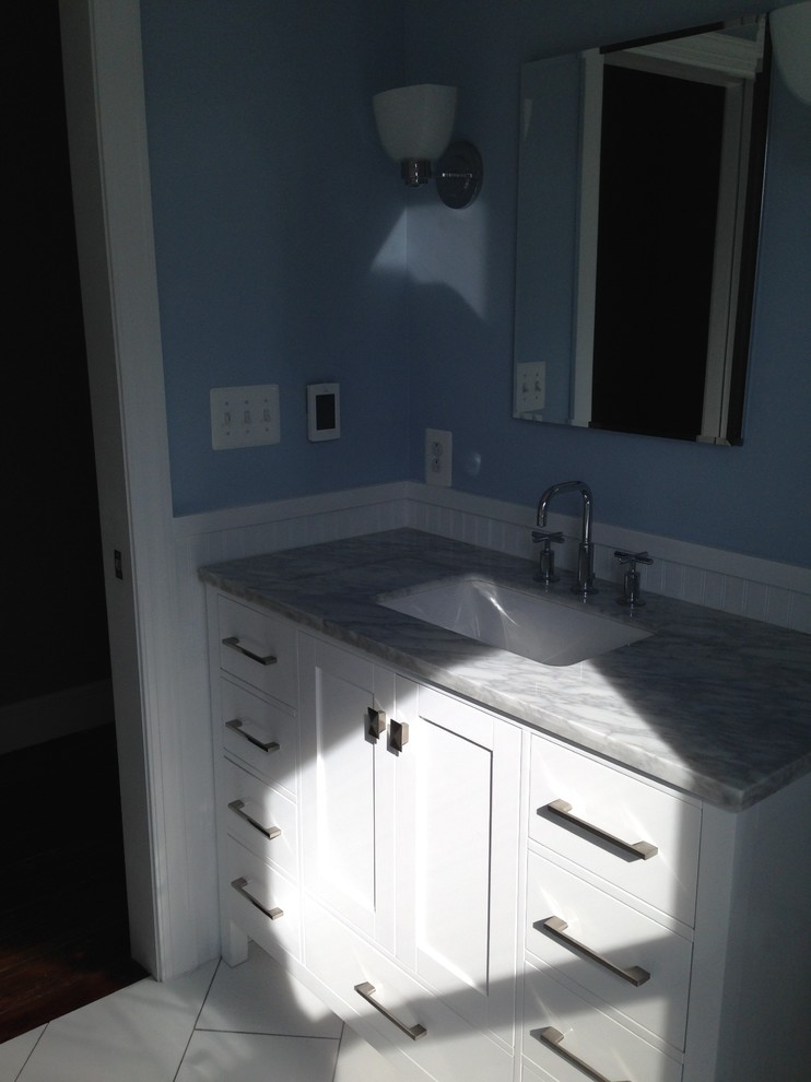 Cette photo montre une salle d'eau chic de taille moyenne avec un placard à porte shaker, des portes de placard blanches, une baignoire en alcôve, un combiné douche/baignoire, WC séparés, des carreaux de porcelaine, un mur bleu, un sol en carrelage de céramique, un lavabo encastré, un plan de toilette en marbre, un sol blanc et une cabine de douche avec un rideau.