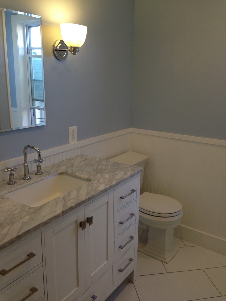 Klassisk inredning av ett mellanstort badrum med dusch, med skåp i shakerstil, vita skåp, marmorbänkskiva, ett badkar i en alkov, en dusch/badkar-kombination, porslinskakel, en toalettstol med separat cisternkåpa, blå väggar, klinkergolv i keramik, ett undermonterad handfat, vitt golv och dusch med duschdraperi