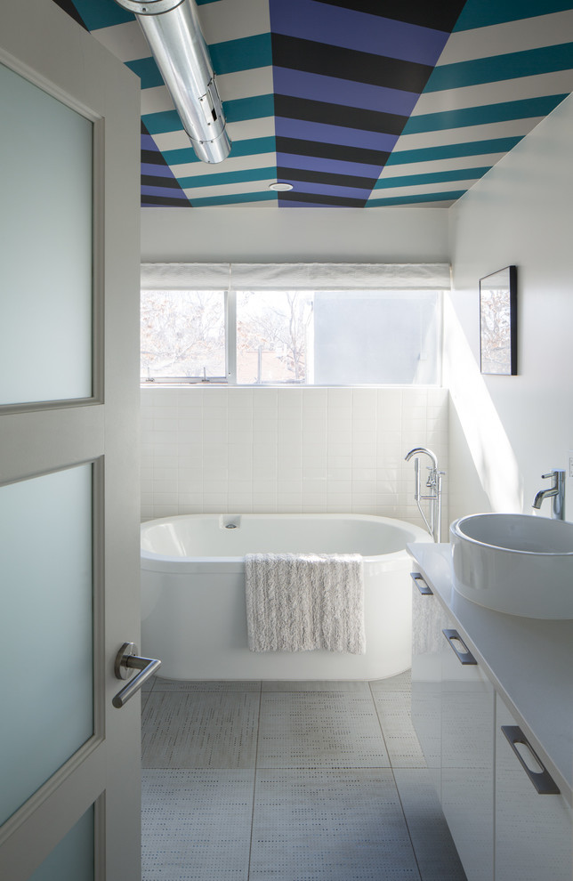 Réalisation d'une salle de bain design avec une vasque, un placard à porte plane, des portes de placard blanches, une baignoire indépendante, un carrelage blanc, un carrelage métro et un mur blanc.