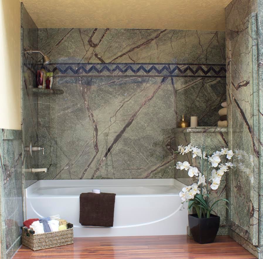 Cette image montre une salle d'eau méditerranéenne de taille moyenne avec un combiné douche/baignoire, un carrelage marron, un carrelage vert, des dalles de pierre, un mur beige, un sol en bois brun, une baignoire en alcôve, un sol marron et une cabine de douche avec un rideau.