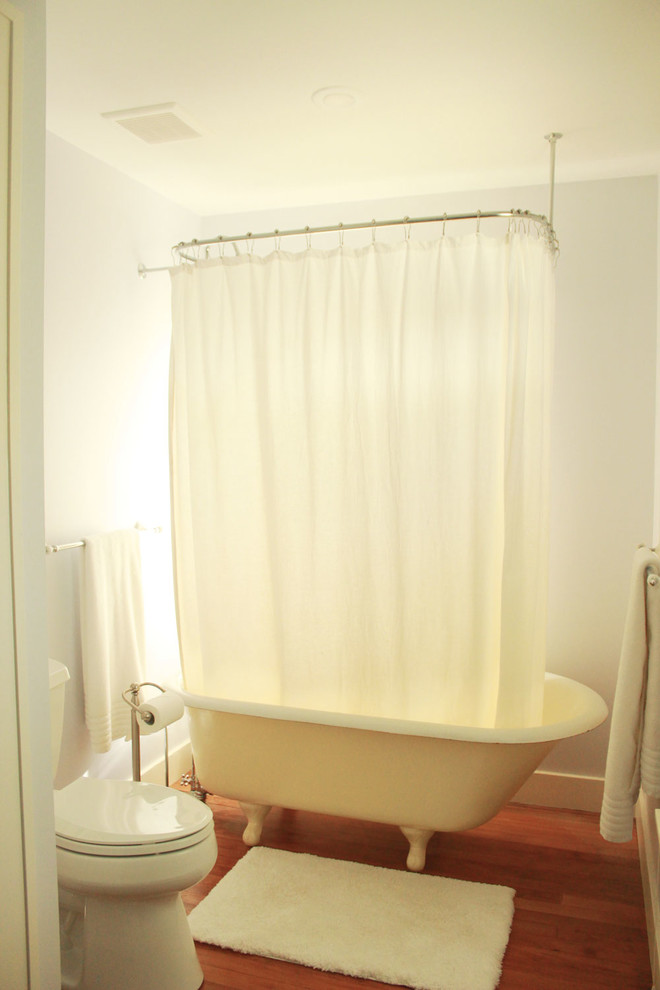 Inspiration för ett mellanstort vintage beige beige en-suite badrum, med ett badkar med tassar, en dusch/badkar-kombination, en toalettstol med separat cisternkåpa, grå väggar, mellanmörkt trägolv, brunt golv, dusch med duschdraperi, luckor med upphöjd panel, skåp i mörkt trä, bänkskiva i kalksten och ett fristående handfat