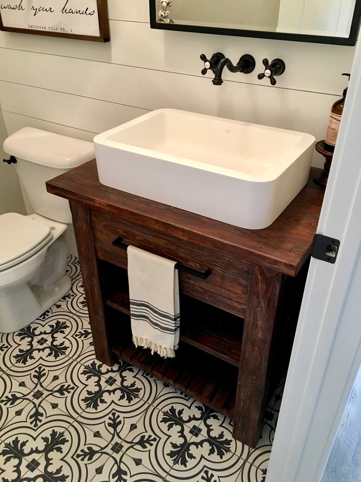Bild på ett litet lantligt brun brunt badrum med dusch, med öppna hyllor, skåp i mörkt trä, en toalettstol med hel cisternkåpa, grå väggar, mosaikgolv, ett avlångt handfat, träbänkskiva och svart golv