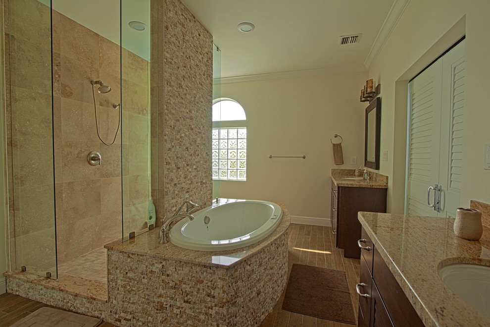 Aménagement d'une salle de bain principale classique en bois foncé avec un placard à porte persienne, un plan de toilette en granite, une baignoire posée et une douche ouverte.