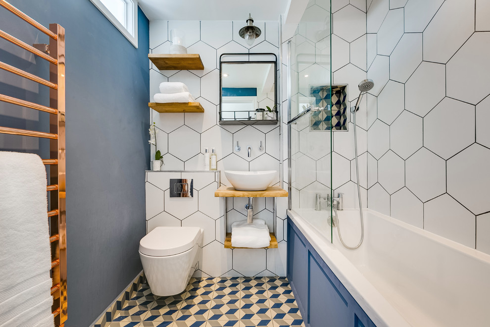 Идея дизайна: ванная комната в стиле неоклассика (современная классика) с открытыми фасадами, накладной ванной, душем над ванной, инсталляцией, белой плиткой, синими стенами, настольной раковиной, столешницей из дерева и разноцветным полом