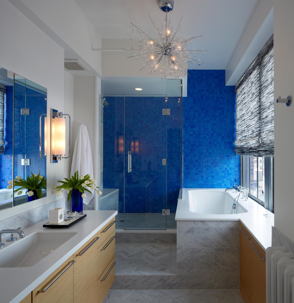 Réalisation d'une salle de bain design en bois clair avec un lavabo encastré, un placard à porte plane, une baignoire encastrée, une douche d'angle, un carrelage bleu et un mur blanc.