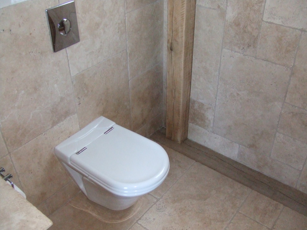 Exemple d'une salle de bain chic en bois brun de taille moyenne avec une vasque, un placard en trompe-l'oeil, une baignoire posée, WC suspendus, un carrelage beige, un carrelage de pierre, un mur beige et un sol en travertin.