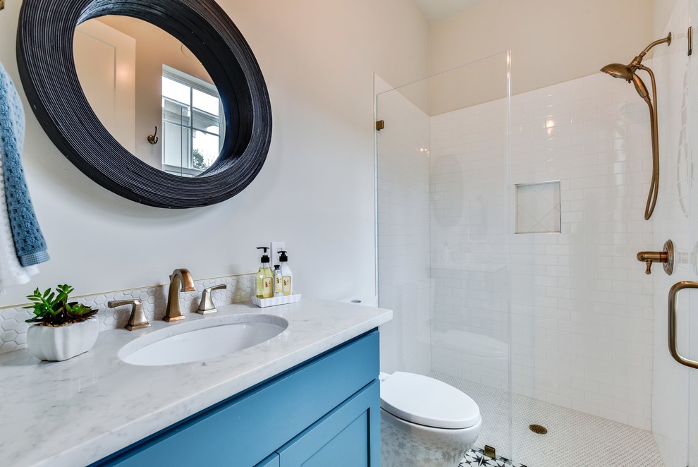 На фото: ванная комната среднего размера в стиле неоклассика (современная классика) с фасадами в стиле шейкер, синими фасадами, двойным душем, унитазом-моноблоком, зеленой плиткой, стеклянной плиткой, белыми стенами, полом из цементной плитки, душевой кабиной, накладной раковиной, столешницей из искусственного кварца, черным полом, душем с распашными дверями и белой столешницей с