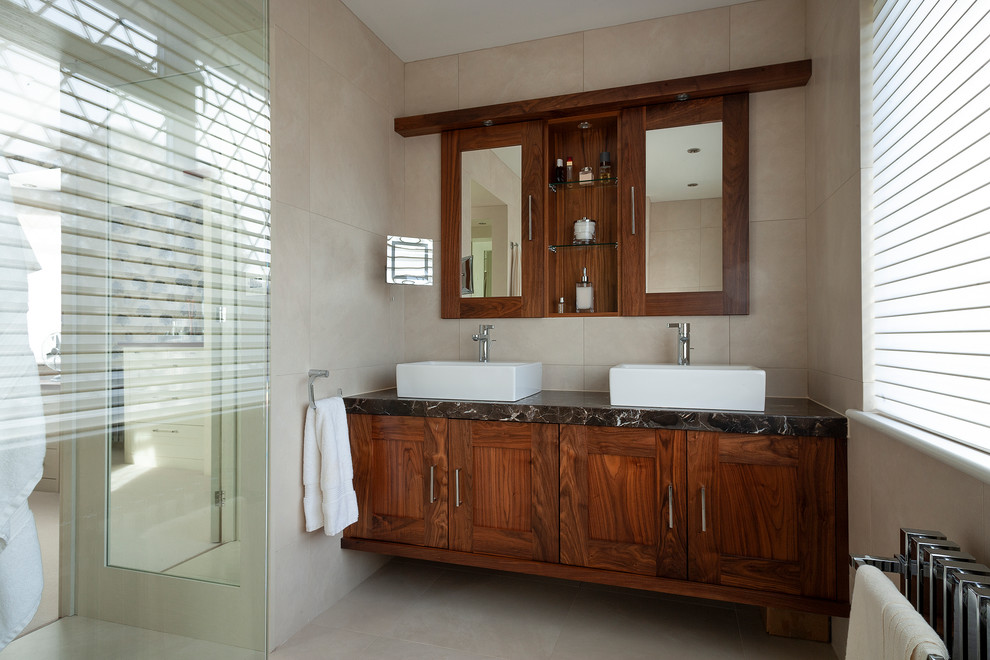 This is an example of a small traditional ensuite bathroom in Other with shaker cabinets, dark wood cabinets, beige tiles, travertine tiles, beige walls, travertine flooring, granite worktops, a vessel sink, beige floors and black worktops.