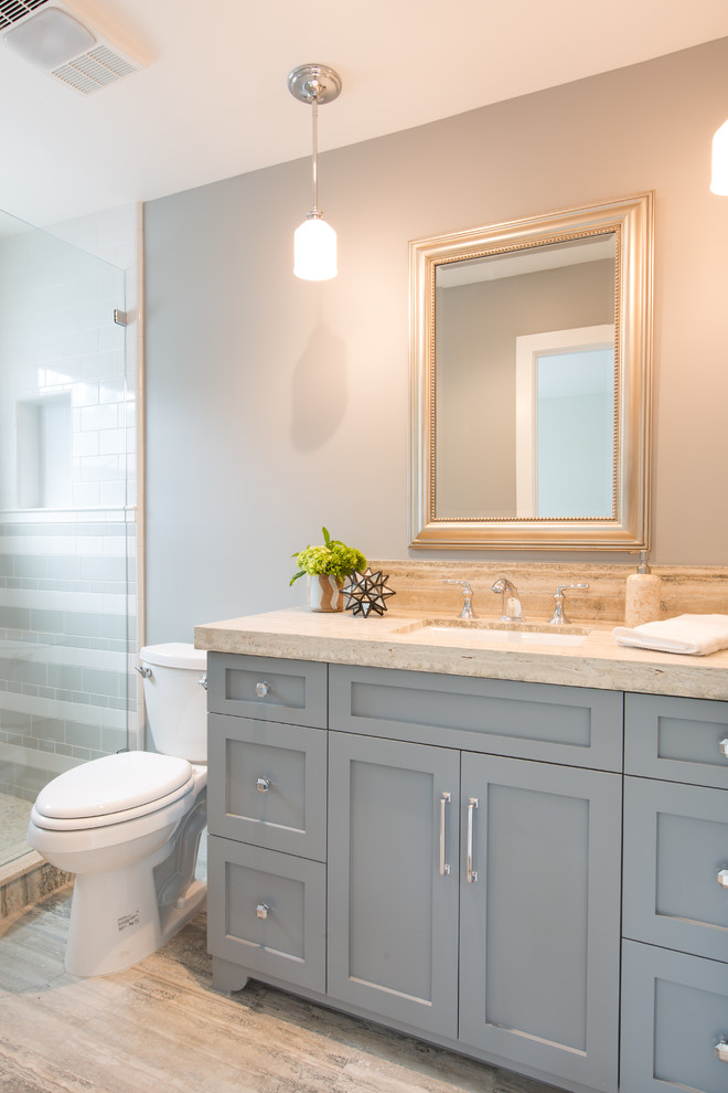Exempel på ett litet maritimt badrum, med luckor med infälld panel, grå skåp, en dusch/badkar-kombination, en toalettstol med hel cisternkåpa, beige kakel, keramikplattor, blå väggar, travertin golv, ett undermonterad handfat och bänkskiva i kalksten