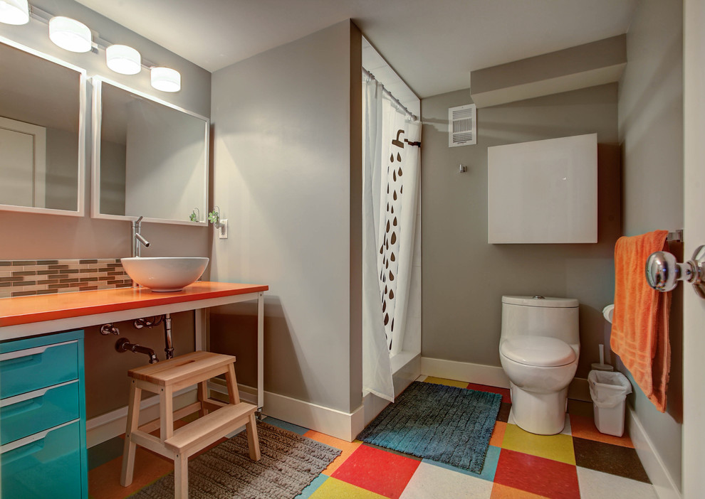 Aménagement d'une douche en alcôve rétro pour enfant avec des portes de placard bleues, WC à poser, un mur gris, une vasque et une cabine de douche avec un rideau.