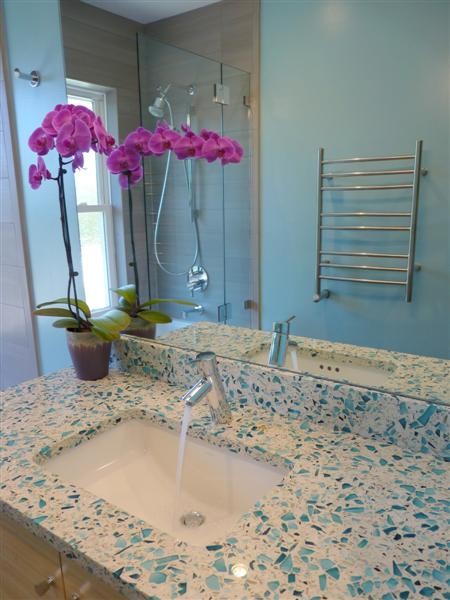 Cette image montre une petite salle de bain design en bois clair pour enfant avec un lavabo encastré, un placard à porte plane, un plan de toilette en verre recyclé, une baignoire en alcôve, un combiné douche/baignoire, WC séparés, un carrelage gris, des carreaux de porcelaine, un mur bleu et un sol en carrelage de porcelaine.