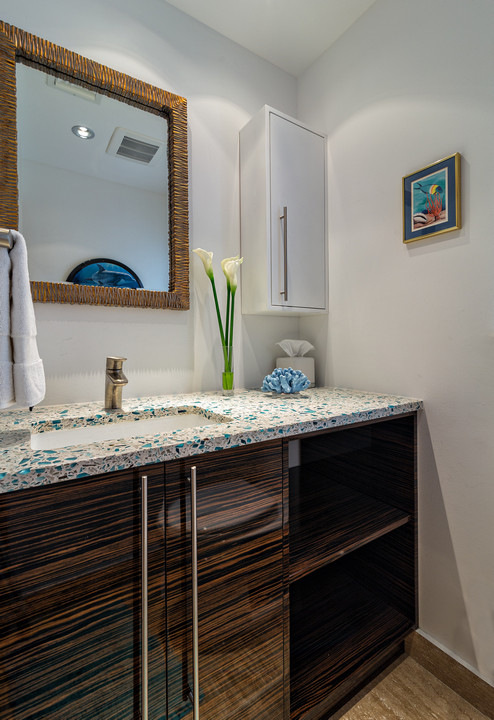 Ispirazione per una stanza da bagno tropicale di medie dimensioni con ante lisce, ante in legno bruno, lavabo sottopiano e top in vetro riciclato