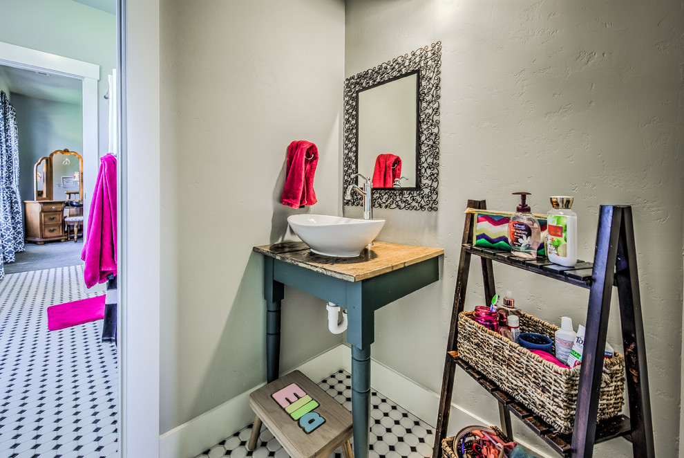 Kleines Country Kinderbad mit Aufsatzwaschbecken, Waschtisch aus Holz, Duschbadewanne, Toilette mit Aufsatzspülkasten, schwarzen Fliesen, grauer Wandfarbe und Keramikboden in Boise