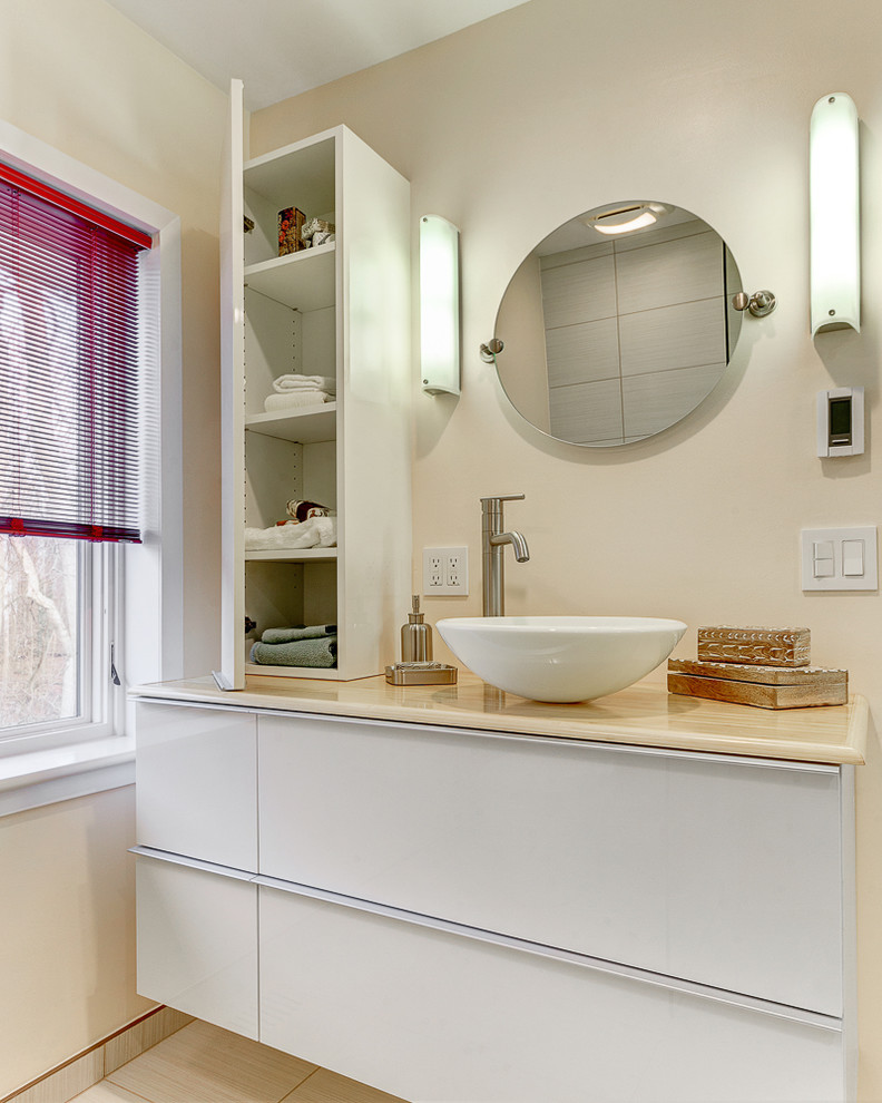 Bild på ett mellanstort funkis en-suite badrum, med ett fristående handfat, släta luckor, vita skåp, träbänkskiva, en kantlös dusch, en toalettstol med separat cisternkåpa, beige kakel, cementkakel, gula väggar och klinkergolv i keramik