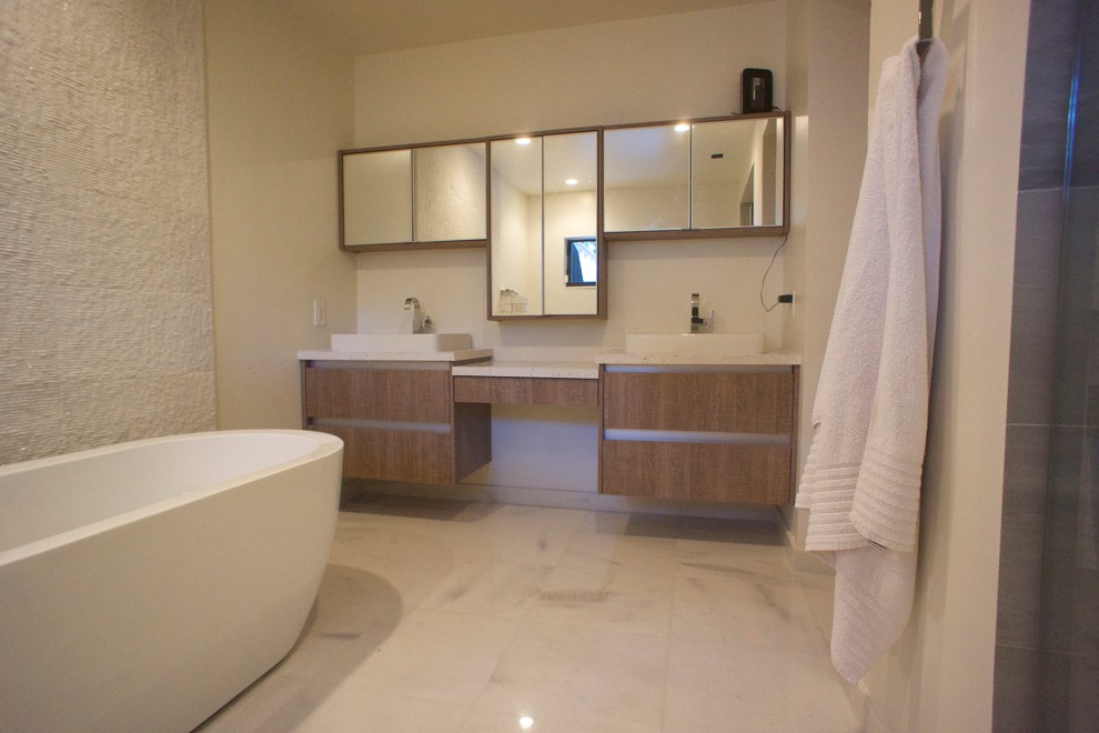 Réalisation d'une salle de bain principale minimaliste en bois brun de taille moyenne avec un placard à porte plane, une baignoire indépendante, un carrelage blanc, un mur blanc, un sol en carrelage de porcelaine et un lavabo posé.
