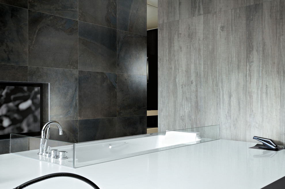 Réalisation d'une salle de bain minimaliste avec une baignoire encastrée, une douche à l'italienne, un carrelage gris et des carreaux de porcelaine.
